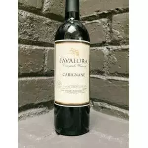 A 2017 Favalora Carignan bottle showcases itself against a brick wall.