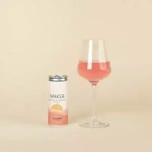 A glass of wine next to a Maker Wine Rose of Grenache by Ser Winery (1 Can) for a refreshing experience.