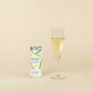 A glass of Maker Wine Sparkling Sauvignon Blanc by Chris Christensen next to a can of lemonade.