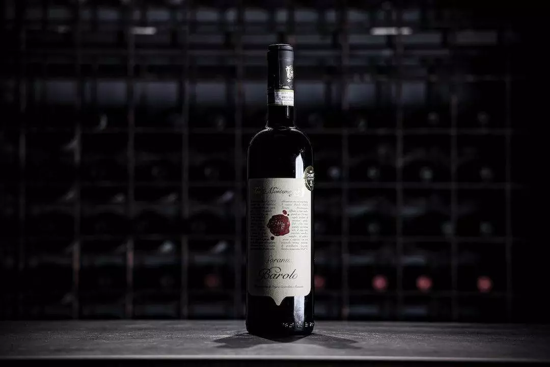 A bottle of wine sitting on a table in a dark room.