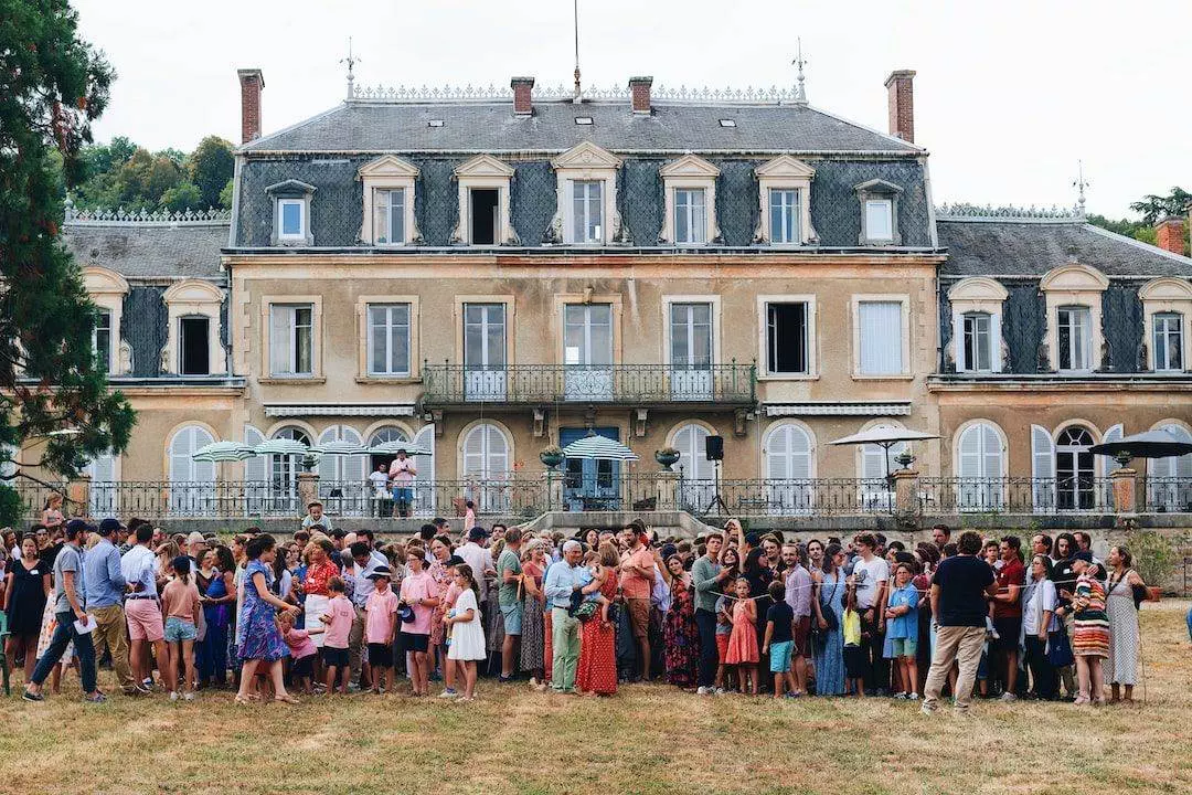 A group of people standing in front of a large mansion.