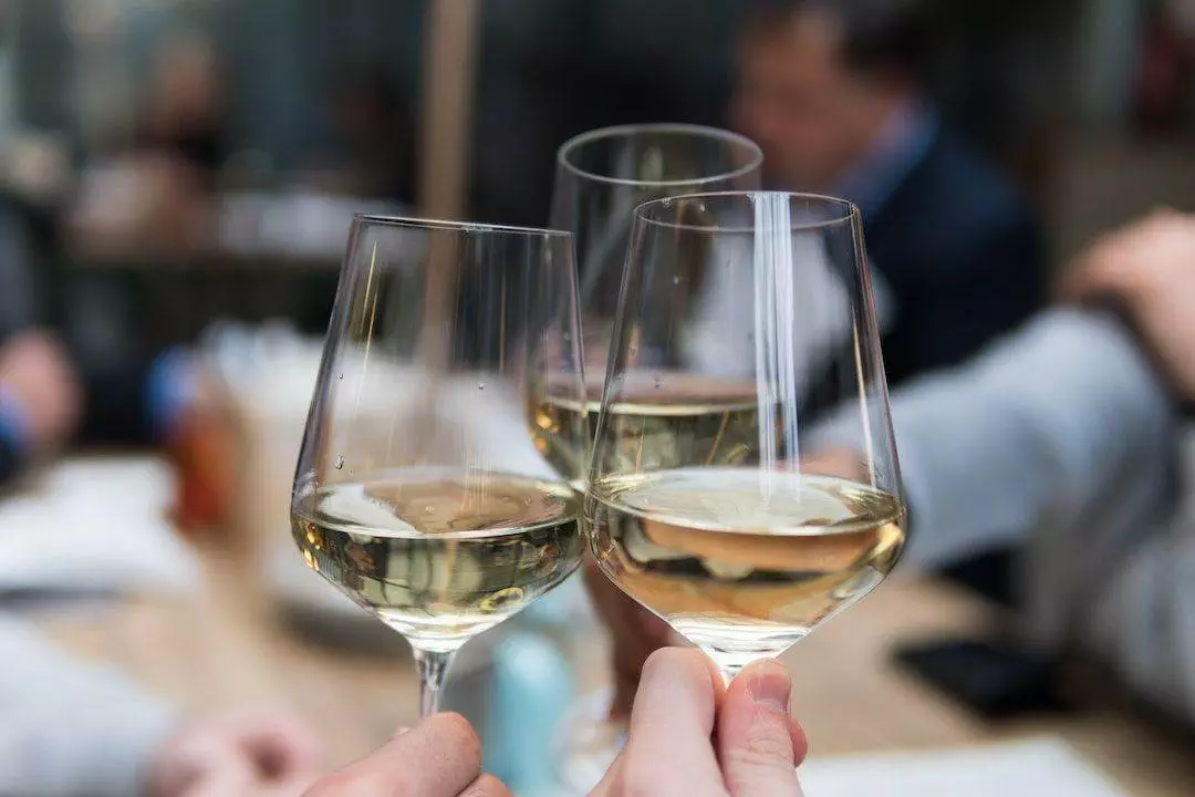 Two people toasting wine glasses at a restaurant.