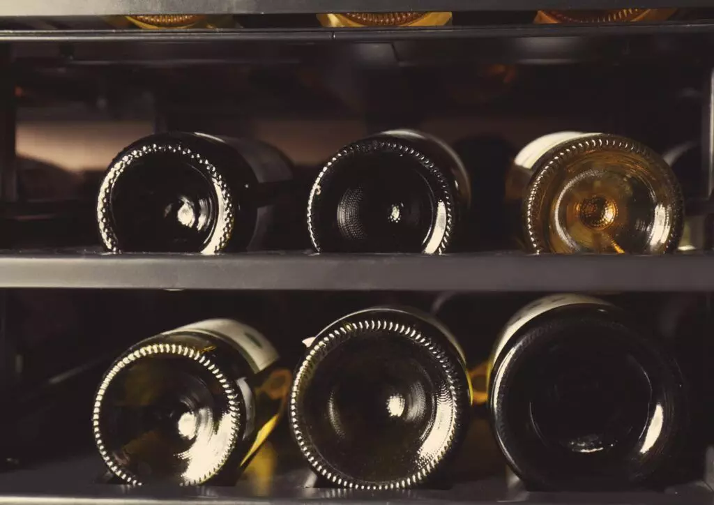 A close-up view of wine bottles stored horizontally in a wine rack, showcasing assorted bottles with different colored contents and necks facing outward. This setup ensures each bottle can gracefully age, reflecting the meticulous care taken in selecting premium Wine Hardware.