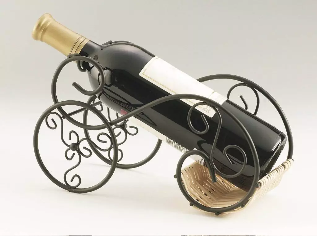 A wine bottle with a golden cap is elegantly displayed in an ornate black metal wine rack featuring spiral designs, offering both beauty and space-saving tips for your home.