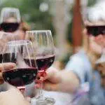 Group of people clinking glasses of red wine outdoors.