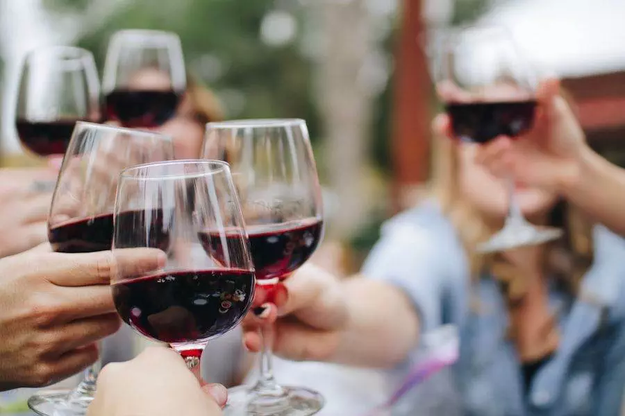 Group of people clinking glasses of red wine outdoors.