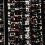 Rows of wine bottles stored horizontally in a temperature-controlled cellar with dark shelves.